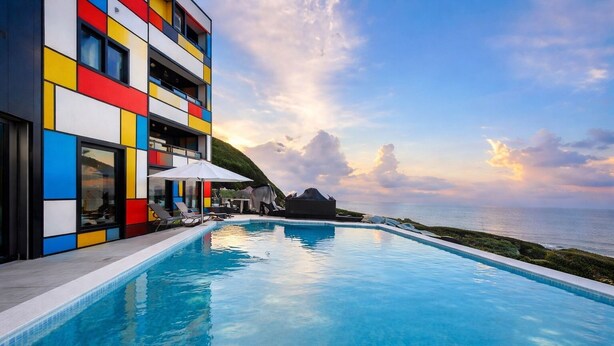A modern hotel with a pool, colorful exterior, and a view of the sea. - House16 (Lyudao)