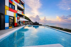 A modern hotel with a pool, colorful exterior, and a view of the sea. - House16 (Lyudao)