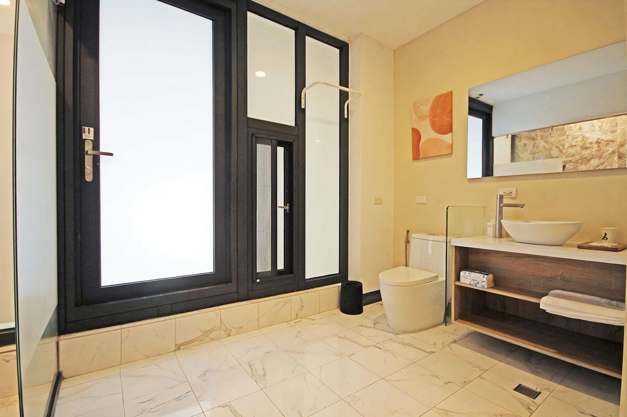 Un baño con un ventanal amplio, un lavamanos y un inodoro.