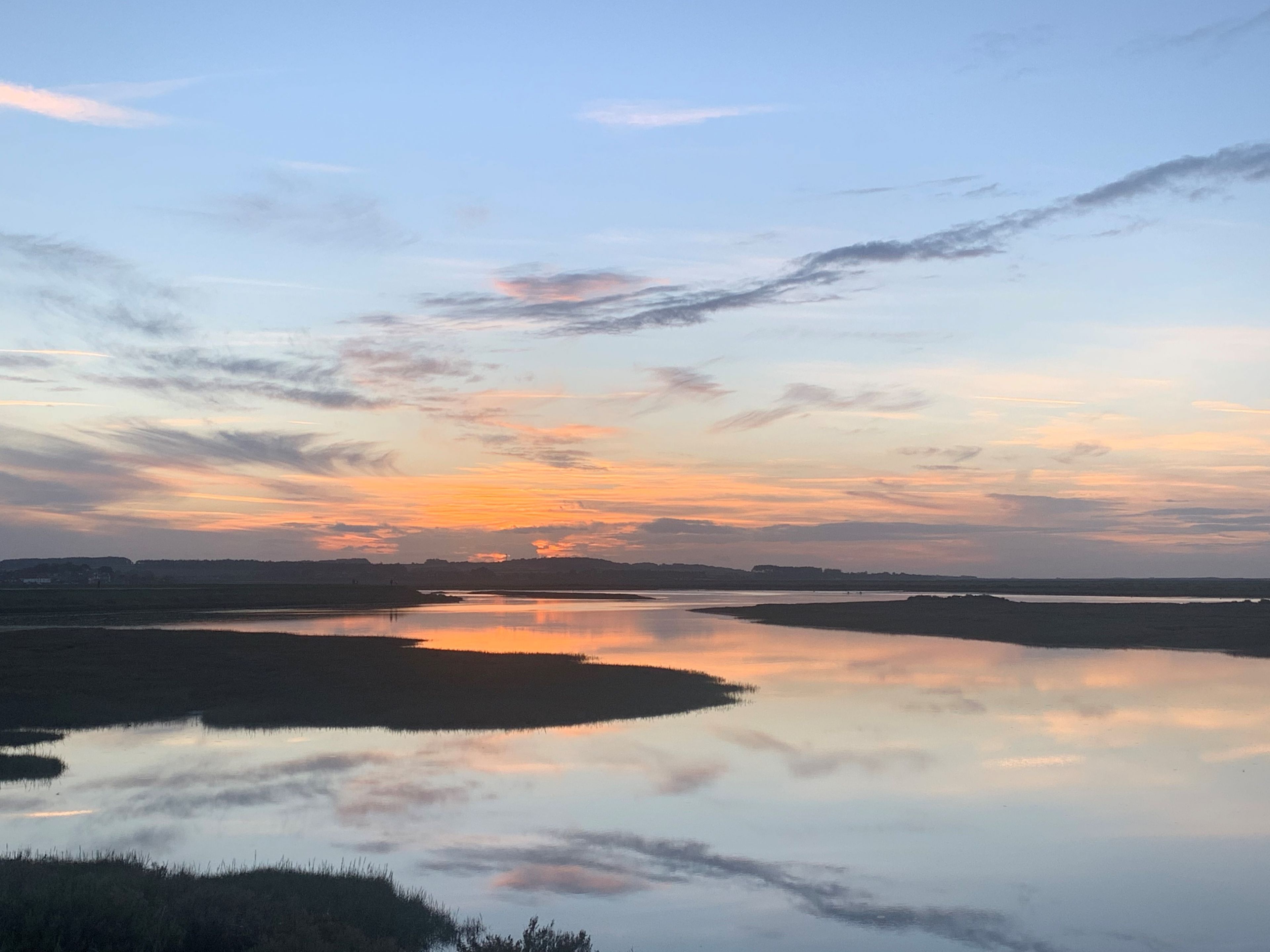 Une étendue d'eau calme qui reflète le ciel au coucher du soleil.