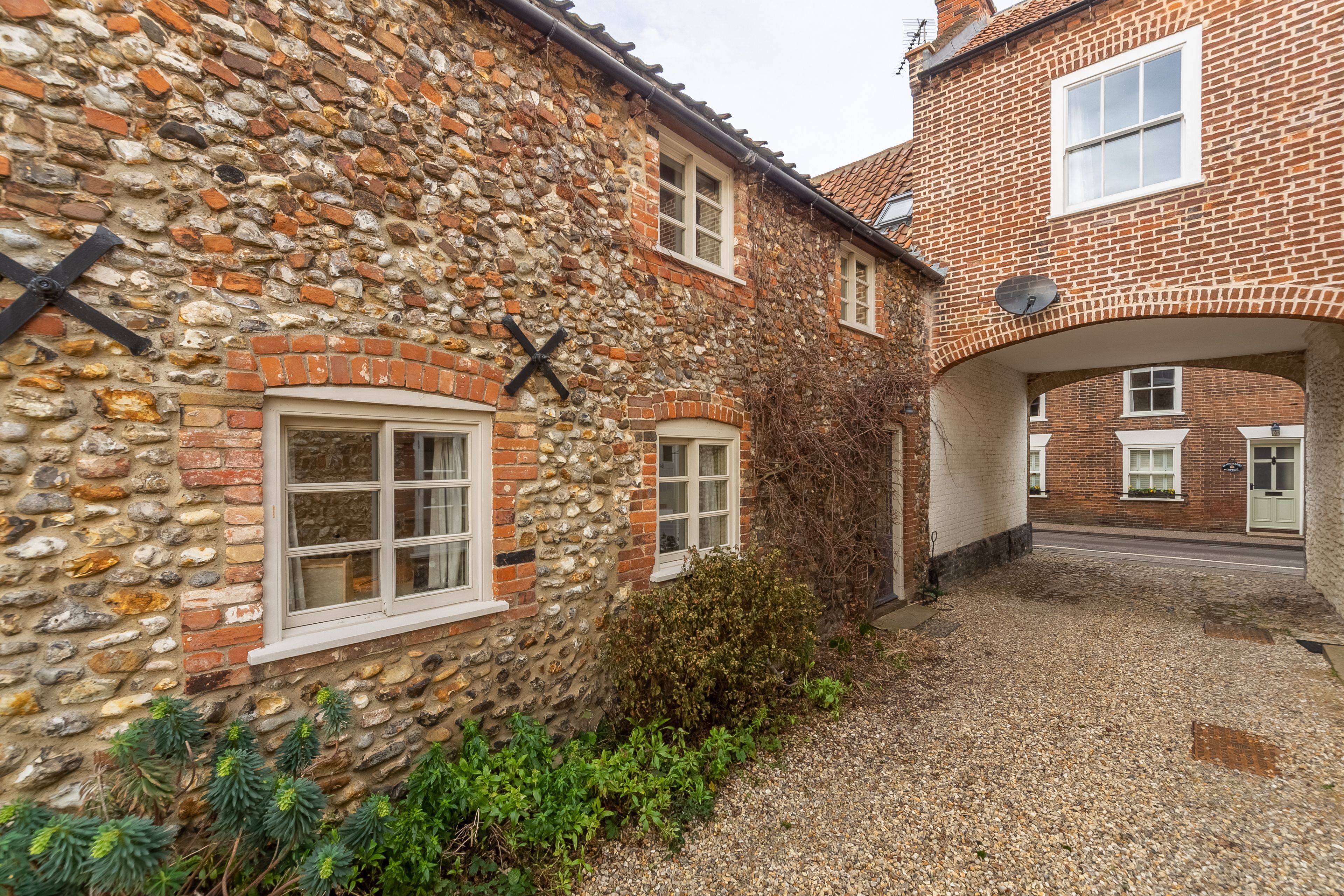 A stone building with a gravel driveway and a brick archway.