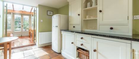Una cocina con armarios blancos, un refrigerador y un comedor con mesa y sillas.