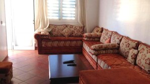A living room with a sofa set, a coffee table, and a window with curtains. - Residence Java Rasmile 2900 (Mdiq)