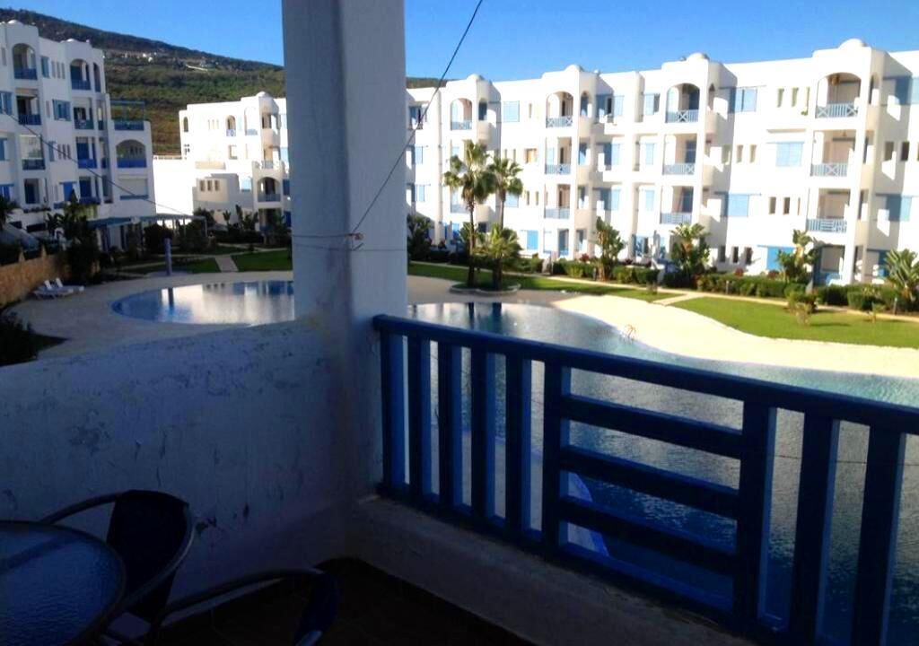 Un hôtel composé de plusieurs bâtiments blancs, doté d’une piscine et bordé de palmiers.
