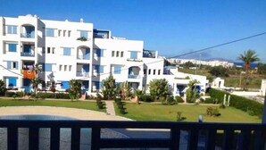 A modern white building with balconies, a well-maintained lawn, and a clear view of the sea. - Residence Java Rasmile 2900 (Mdiq)