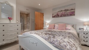 A bedroom with a bed, dresser, nightstand, and a shower. - The Moorings, Wells-next-the-Sea, Norfolk (Wells-next-the-Sea)
