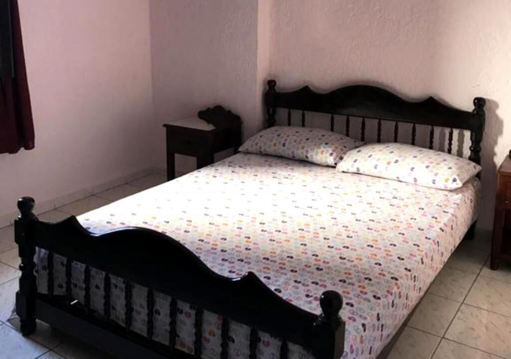 Uma cama de solteiro com cabeceira de madeira e colcha estampada.