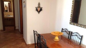 A dining area with a wooden table and chairs, a decorative centerpiece, and a mirror on the wall. - Residence Java Rasmile 2846 (Mdiq)