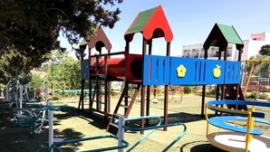 Une aire de jeux équipée d’une structure d’escalade, d’un toboggan et d’appareils de musculation.