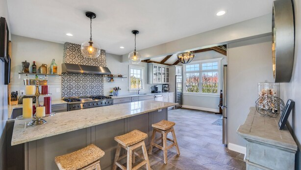A spacious kitchen with a large island, pendant lighting, and a view to the outside.