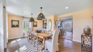 A spacious dining area with a large wooden table, multiple chairs, and a patterned rug.