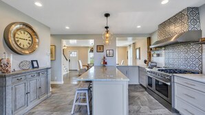 A spacious kitchen with a large island, modern appliances, and a decorative clock.