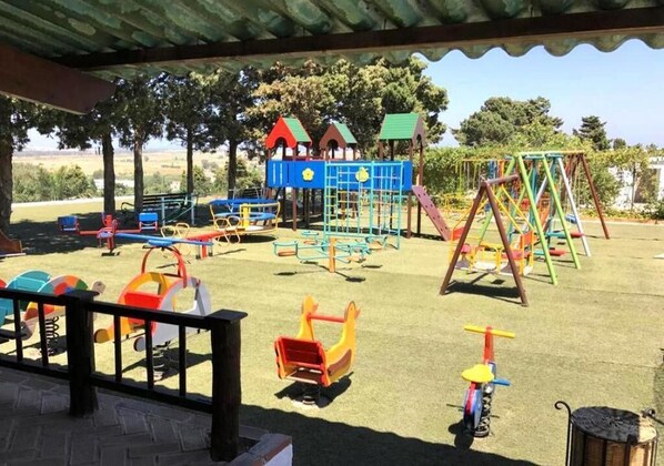 A playground with various play structures including slides, swings, and climbing frames.