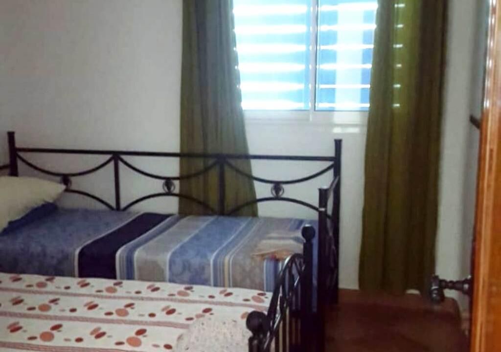 A bedroom with a bed, curtains, and a window.