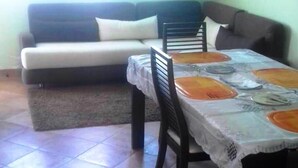 A dining area with a table set for four, a sofa, and a rug in a living room. - Residence Java Rasmile 2899 (Mdiq)