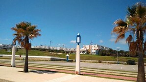 A paved walkway with palm trees, a street lamp, and buildings in the background. - Residence Java Rasmile 2899 (Mdiq)