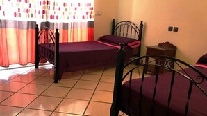 Habitación con dos camas, ventana con cortinas y piso de baldosas.