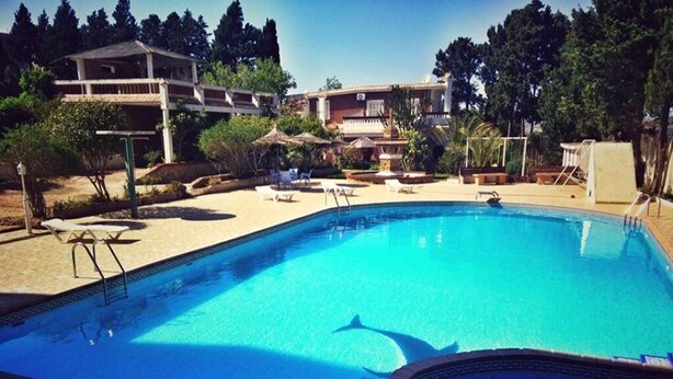 Piscina con sillones de descanso y una pequeña cascada.