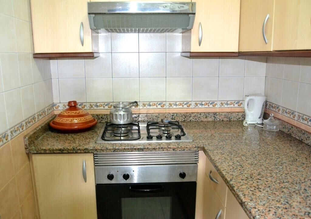 A kitchen with a gas stove, oven, and a decorative pot on the counter.