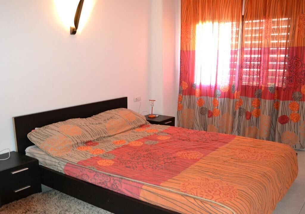 A bedroom with a bed, nightstand, and a lamp.