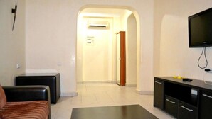 Una habitación de hotel con cama, un pequeño sofá, televisión, escritorio y armario.