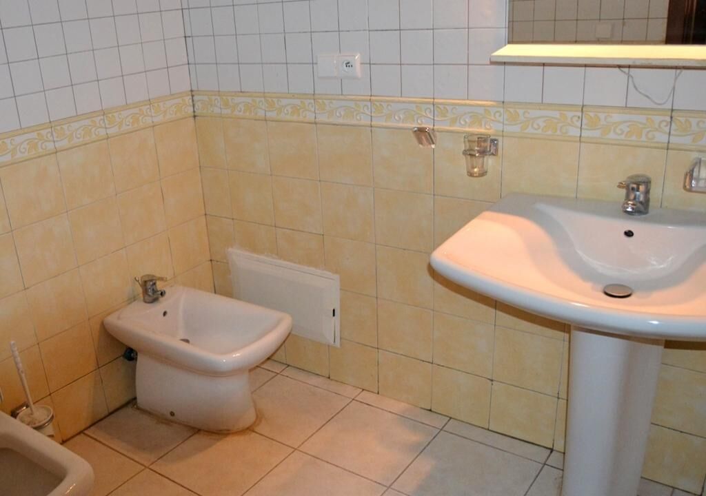 Een badkamer met een hygiëneslot, een wastafel en betegelde muren.