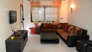 Una sala de estar con un sofá, una mesa de centro y un televisor montado en la pared.