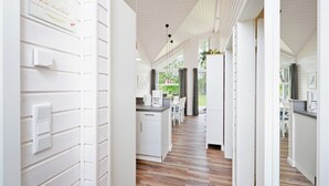 Una cucina moderna con mobili bianchi, pavimento in legno e vista sull'esterno.