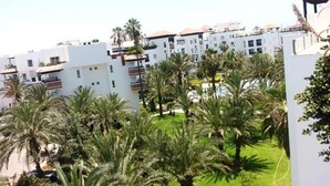 Un quartier résidentiel avec des bâtiments blancs, des palmiers et un ciel dégagé.
