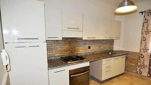 Eine Küche mit weißen Schränken, einer Granitarbeitsplatte, einem Herd und einem Backofen.