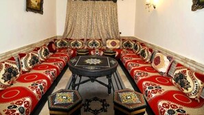 Ein Zimmer mit einer langen, verzierten Couch mit aufwendigen Mustern, einem kleinen runden Tisch und einem dekorativen Teppich.