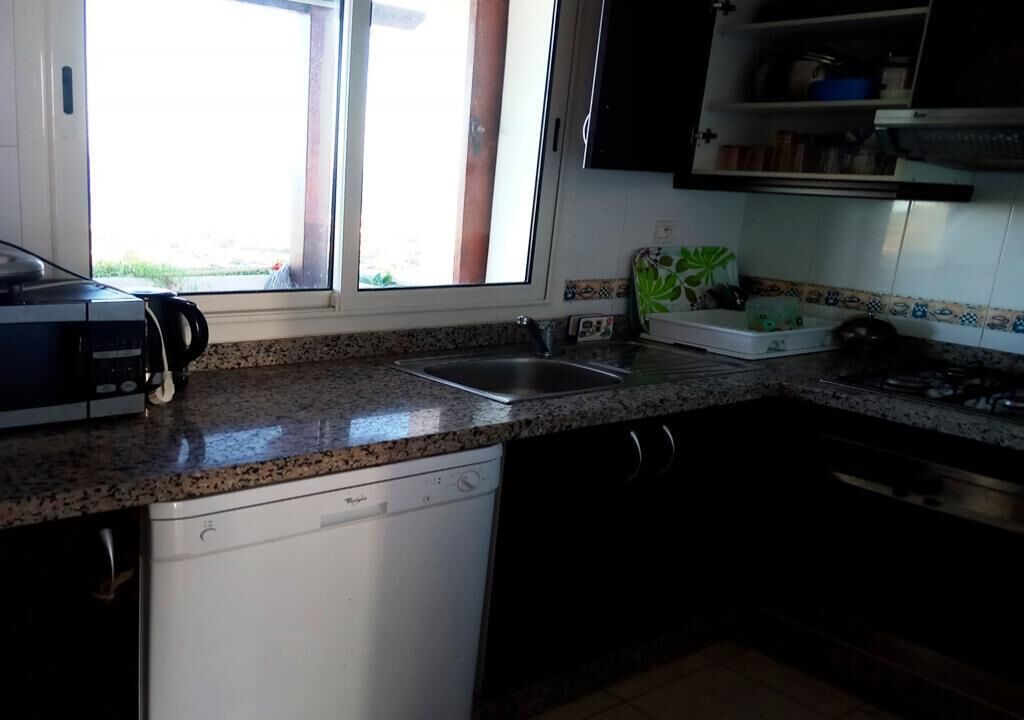 A kitchen with a dishwasher, a sink, and a window with a view of the outdoors.