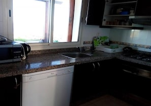 Een keuken met een vaatwasser, een spoelbak en een raam met uitzicht op de omgeving.