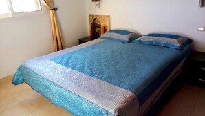 A bedroom with a large bed, a nightstand, a wall-mounted lamp, and a window with curtains. - Bella Vista Cabo 3455 Residence (Cabo Negro)
