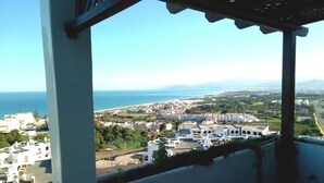 A balcony with a view of a coastal town, buildings, and the sea. - Bella Vista Cabo 3455 Residence (Cabo Negro)