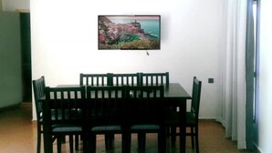 Ein Essbereich mit Tisch und Stühlen, einer Klimaanlage und einem Gemälde einer Küstenstadt an der Wand.