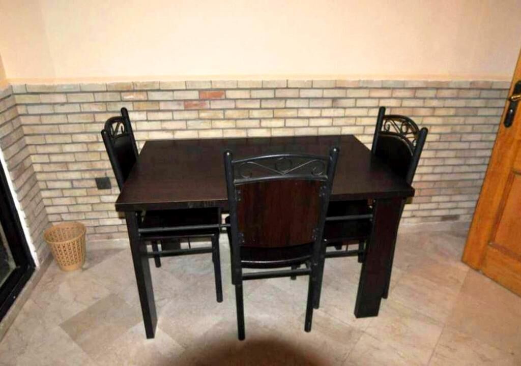 A dining area with a brick wall, a dark wooden table, and four chairs.