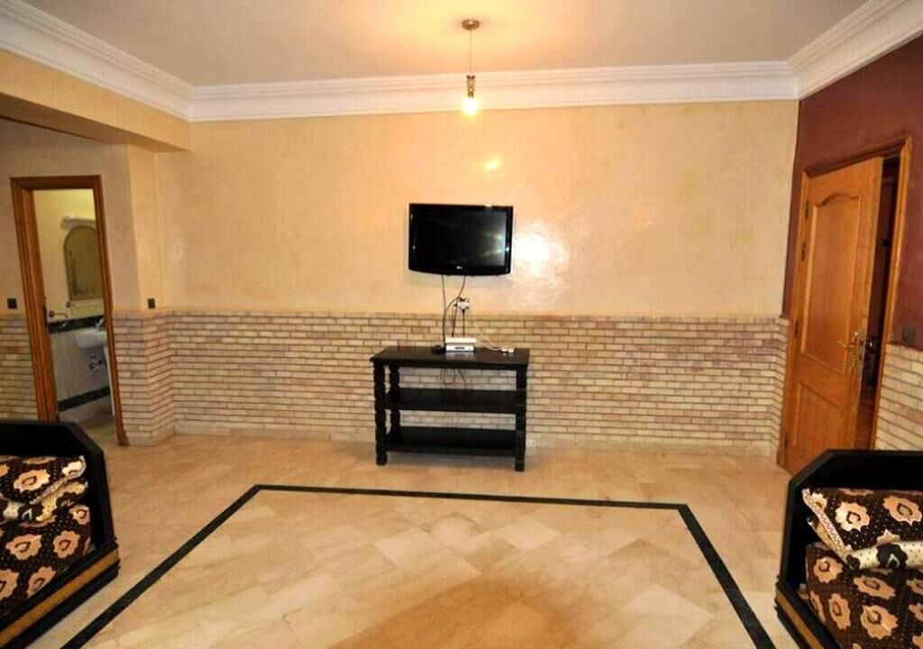 Una sala de estar con un televisor de pantalla plana montado en la pared, un mueble multimedia negro y sofás estampados.