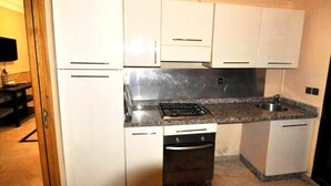A compact kitchen with white cabinets, a built-in oven, and a granite countertop. - Residence Babylone Marrakech 3388 (Marrakech)