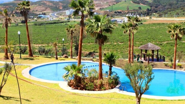 A pool area with palm trees, a gazebo, and a view of distant mountains. - Lilac's Garden Residence 2194 (Cabo Negro)