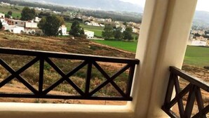 A balcony with a view of a rural landscape, including fields and distant buildings. - Lilac's Garden Residence 2194 (Cabo Negro)