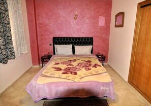 A bedroom with a bed, a nightstand, a wall clock, and a door. - ����������������������������������������������������������������������������������������������������������������������������������������������������������������������������������������� (Marrakech)