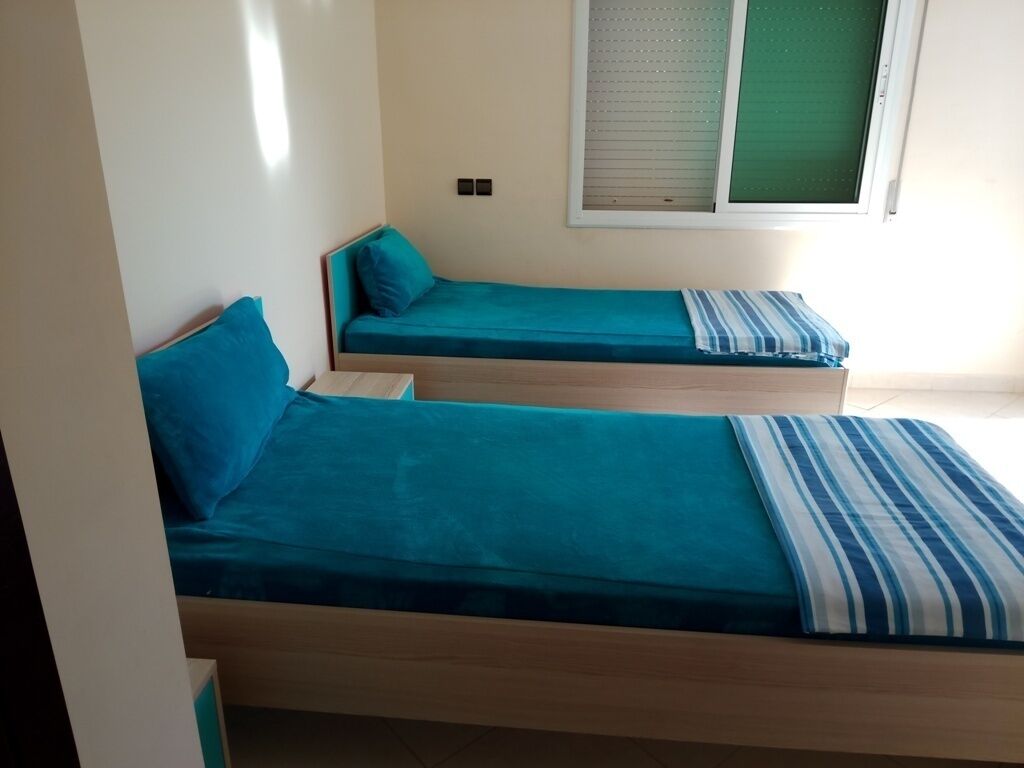 A room with two single beds, each with a blue mattress and matching pillows.