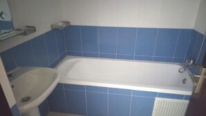 A bathroom with a white bathtub, a white sink, and blue tiles. - Atlantic Ocean Residence 3047 (Asilah)