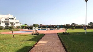 Un sendero conduce a un área de piscina con un edificio al fondo.