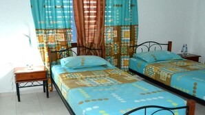 Een slaapkamer met twee bedden, een nachtkastje en een raam met gordijnen.