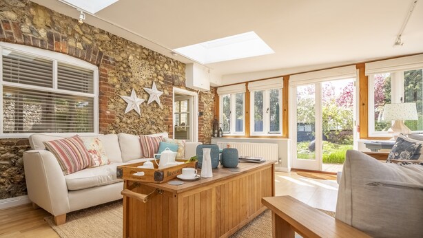A cozy living room with a stone wall, a wooden coffee table, and a comfortable sofa. - The Old Dairy, Great Bircham, Norfolk (Bircham)