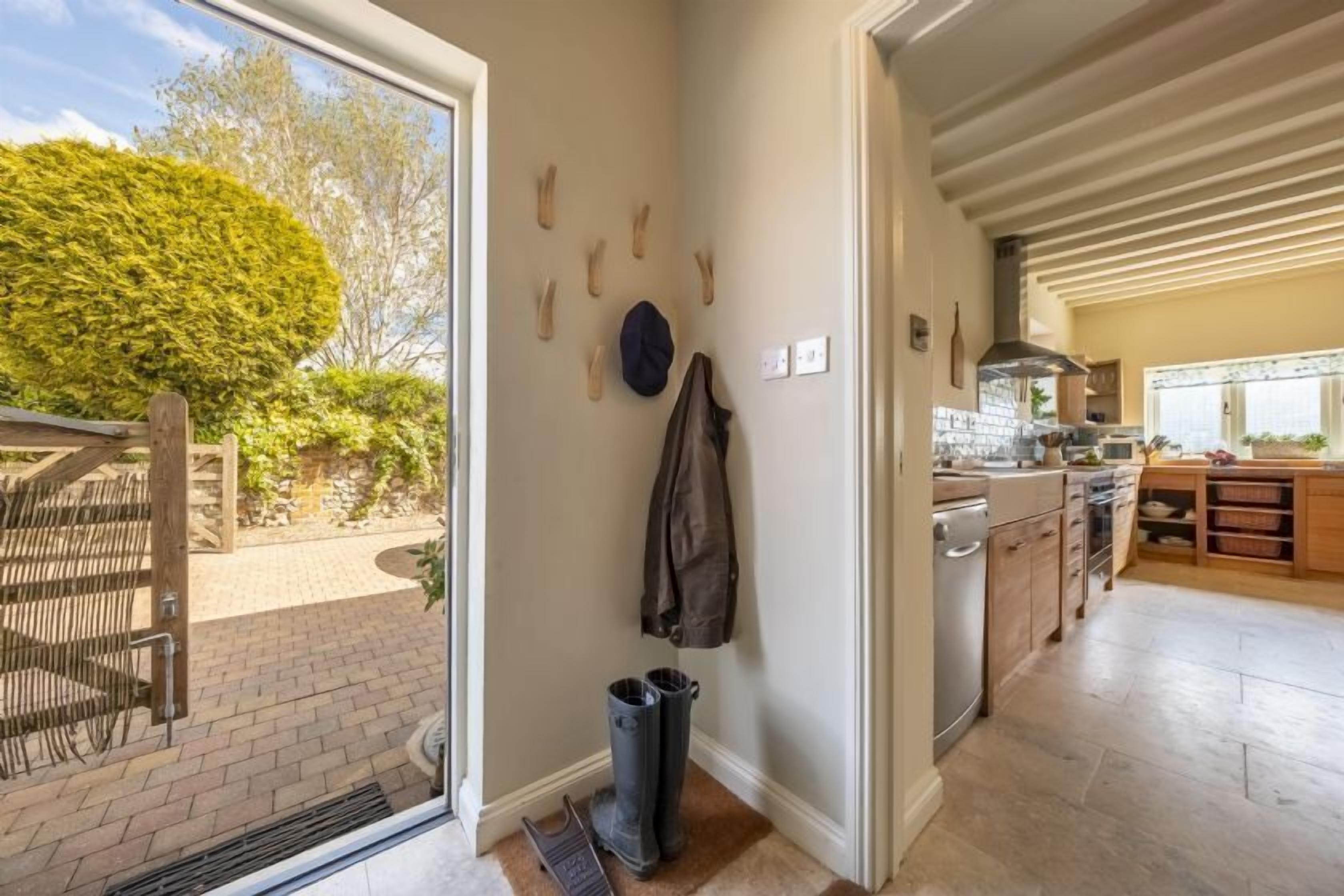 A kitchen with wooden cabinets, a built-in oven, and a window overlooking a garden.