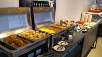 A buffet with various food items including pastries, fruits, and a salad bar.