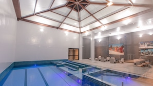 A modern indoor swimming pool with a glass ceiling, seating area, and artwork on the walls. - Dall'Onder Ski Hotel (Garibaldi)